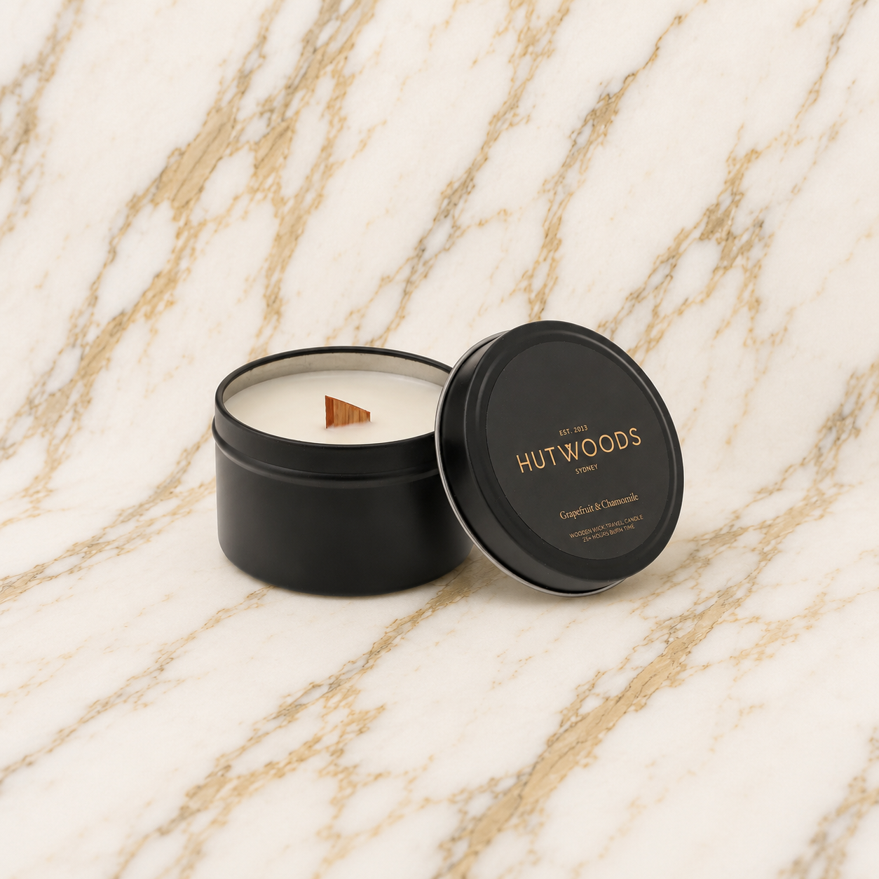 Hutwoods travel candle in a black tin on a marble surface
