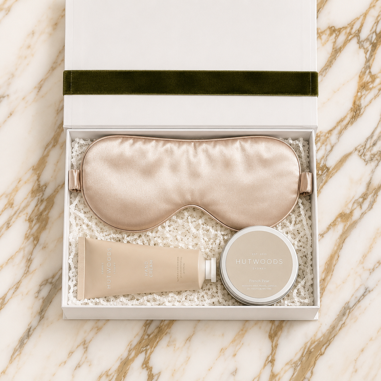 100%Mullberry Silk eye mask, Hutwoods hand cream, and Hutwoods travel candle in a white box on a marble surface